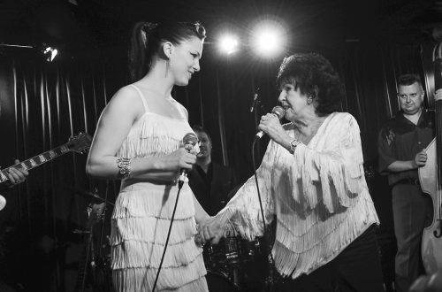 Imelda May and Wanda Jackson holding hands on stage at a gig